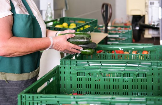 Hände packen Zucchini in eine Kiste