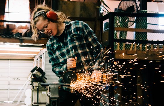 Eine junge Frau arbeit mit einer Flex, so dass starke Funken fliegen