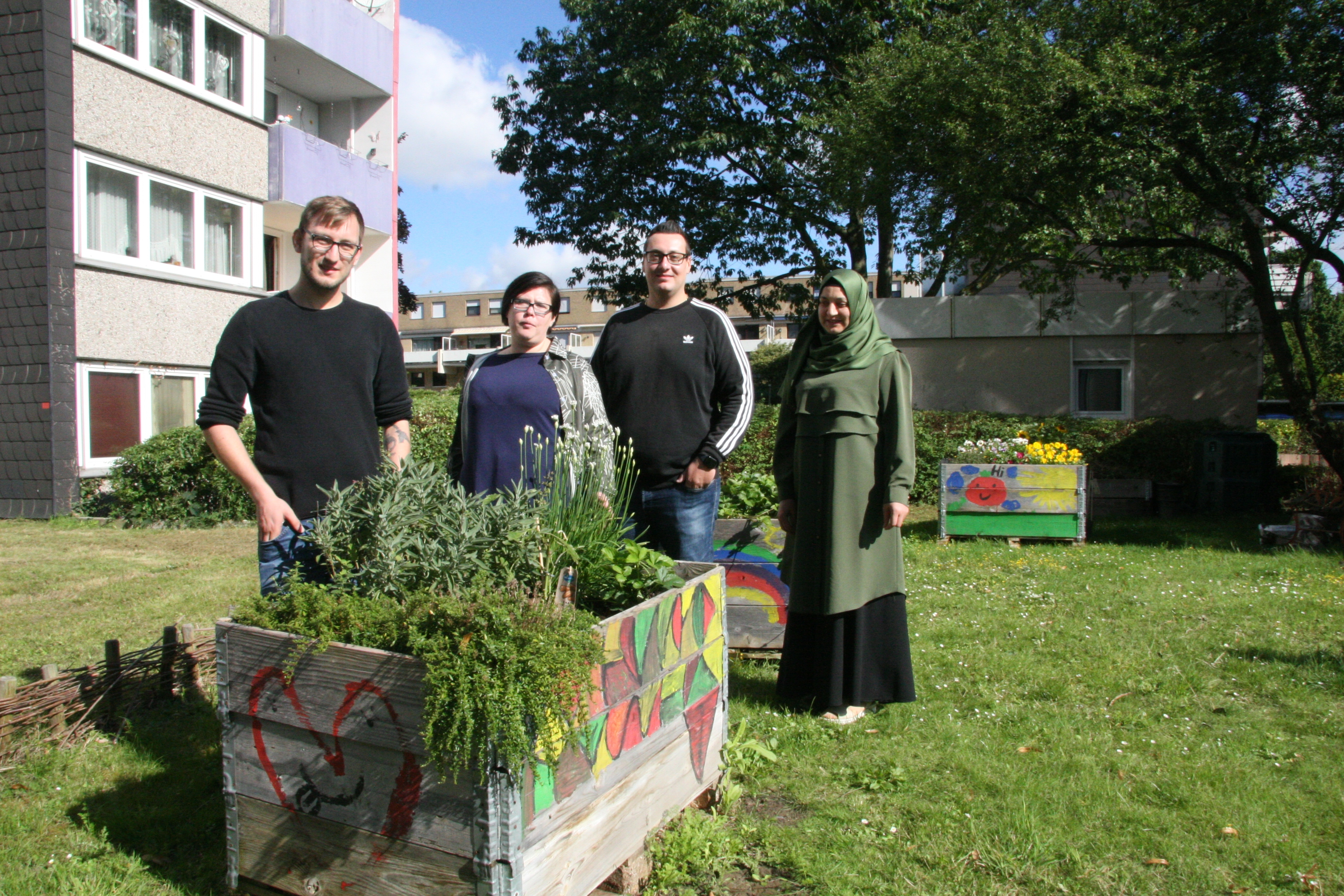 4 Personen stehen hinter einem Hochbeet